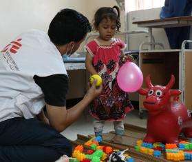 A mental health counselor in Yemen shows a girl a pink balloon.