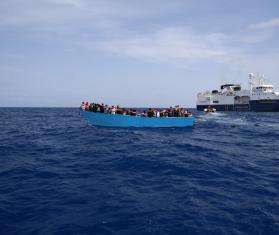 A search and rescue vessel approaches an overcrowded boat in the Mediterranean sea. 