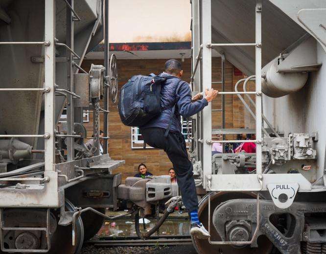 A migrant climbs onto a train in Mexico.