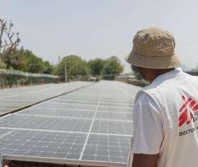 An MSF staff member stands in front of solar panels in Nigeria.