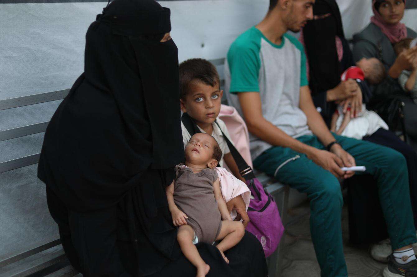 Abeer holds her 3-month-old malnourished daughter, Yasmine, beside her son Mohammed as they wait for care at MSF's Al-Attar clinic in Khan Younis.
