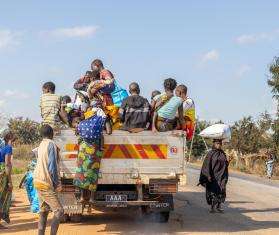 People ride in the back of a truck in Mozambique.