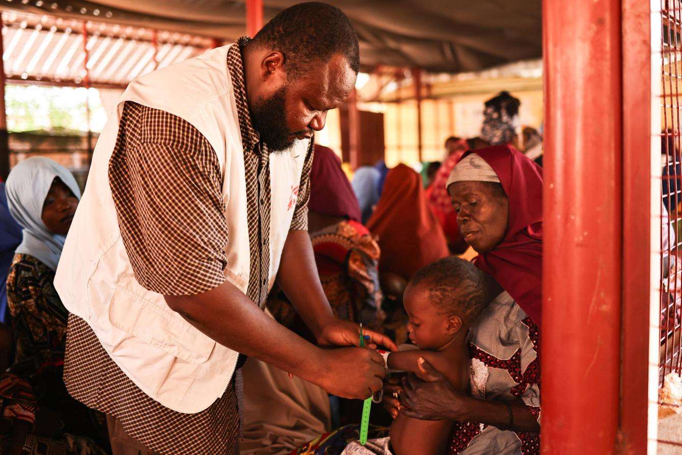 An MSF team member measures the mid-upper arm circumference of 2-year-old Maniru at the outpatient therapeutic feeding center in the Jega local government area, Kebbi state, Nigeria.